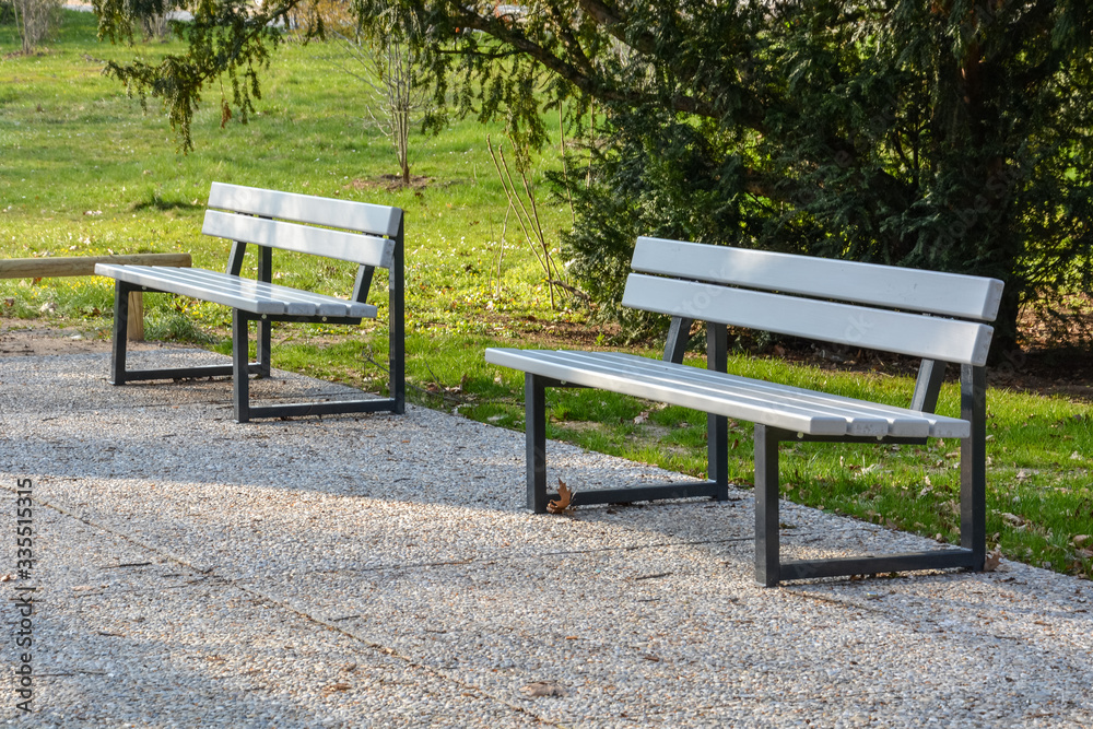 Two benches in a park with sunny weather