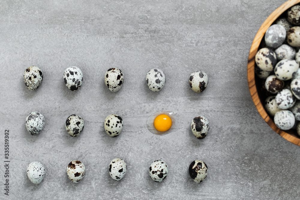 Many quail eggs on gray concrete cement background. One egg broken, orange yolk and protein. Easter cooking concept. Many quail eggs on gray concrete cement background. One egg broken, orange yolk and protein. Easter cooking concept.