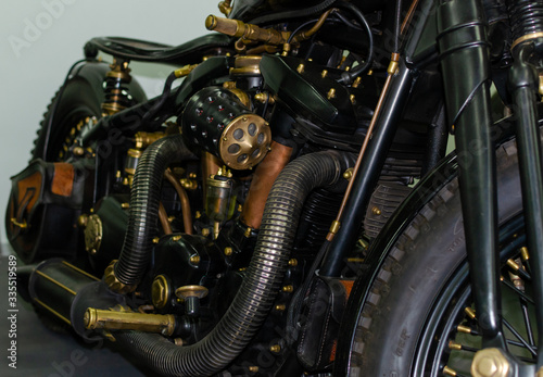 WROCLAW, POLAND - August 11, 2019: USA cars show: Fragment of vintage stylish black and copper coloured engine with exhaust system pipes and side lights of restored motorcycle closeup