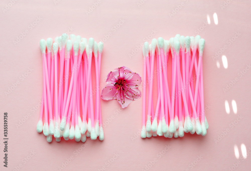 Pink ear sticks and flower bud on a pink background, top view. Cosmetology Pink ear sticks and flower bud on a pink background, top view. Cosmetology