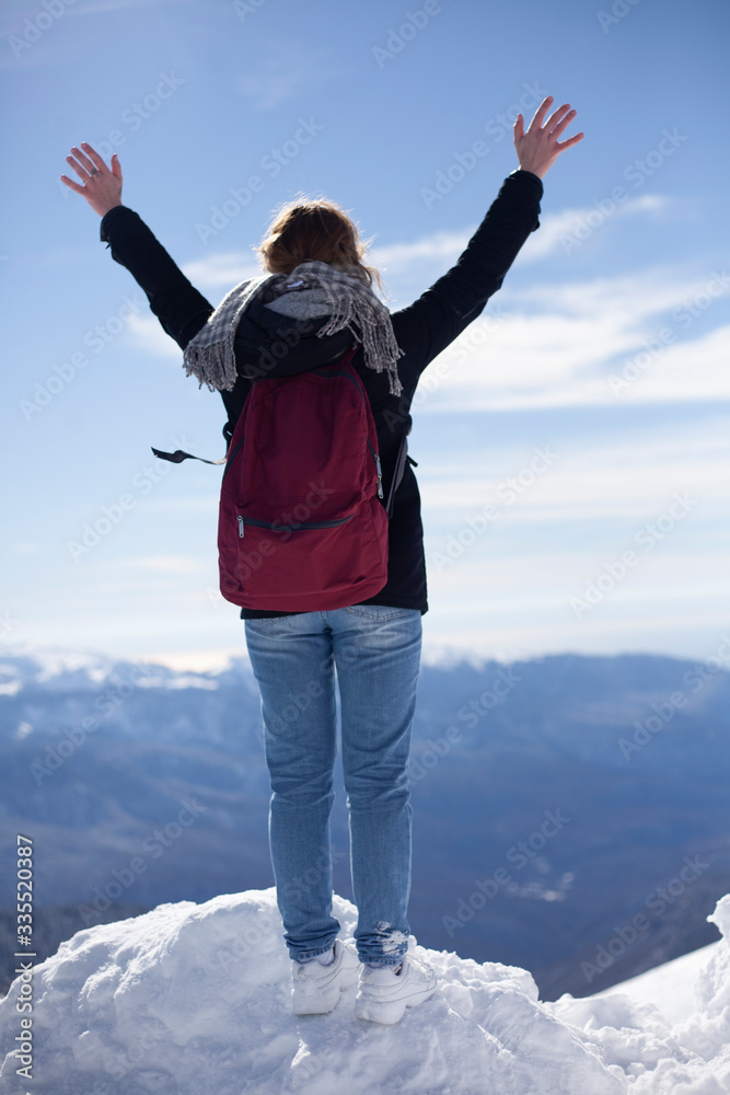 Girl on the mountain raises her hands.
