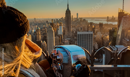 Frau steht vor Fernglas und blickt auf die Skyline von New York City Manhattan