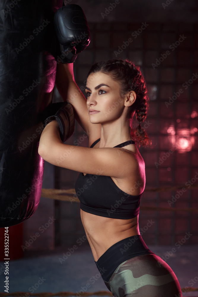 Beautiful slim sexy sportswoman in the ring and the gym in boxing gloves.