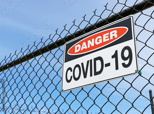 COVID-19 danger sign on fence with blue sky background