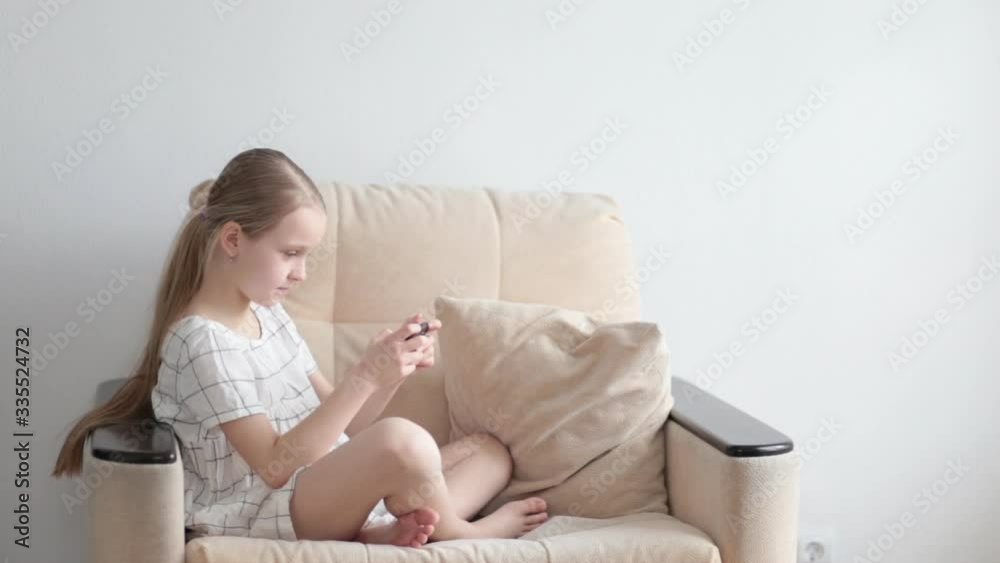 child girl playing in a smartphone sitting in a chair child girl playing in a smartphone sitting in a chair