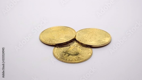 Golden Bitcoin coins rotate on a white background. Footage. 360 rotation.