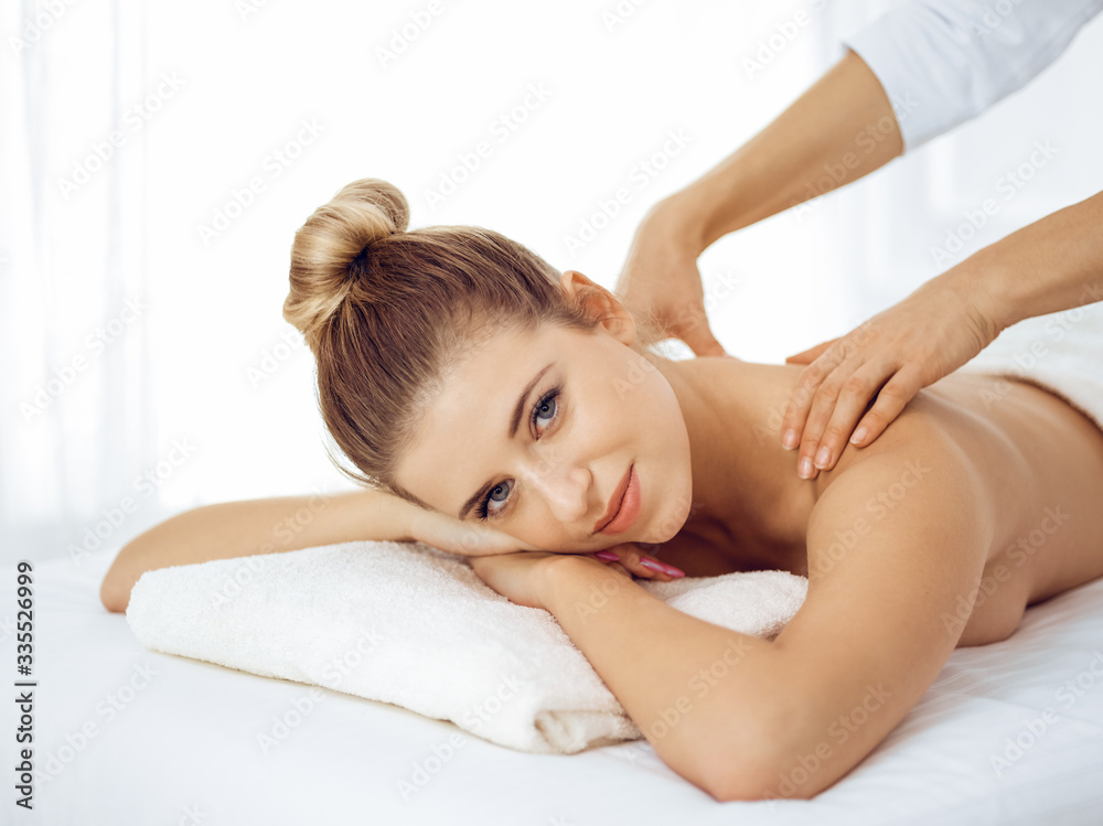 Young and blonde woman enjoying massage of back in spa salon. Beauty concept Young and blonde woman enjoying massage of back in spa salon. Beauty concept