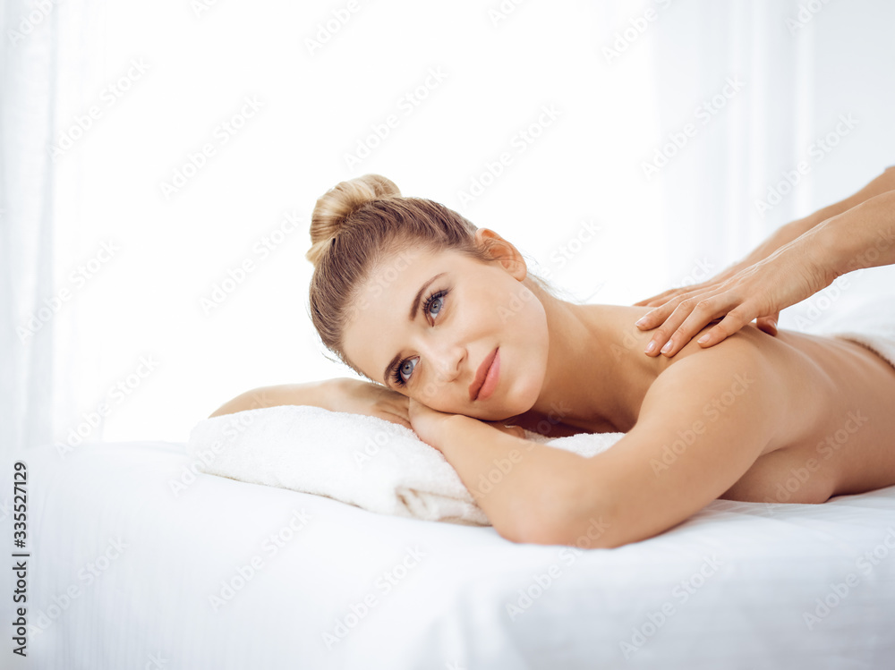 Young and blonde woman enjoying massage of back in spa salon. Beauty concept Young and blonde woman enjoying massage of back in spa salon. Beauty concept
