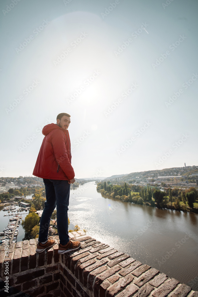 Young man with view of the Prague, Czech Republic. Touristic travel photo conception. Man stand on brick wall near the river