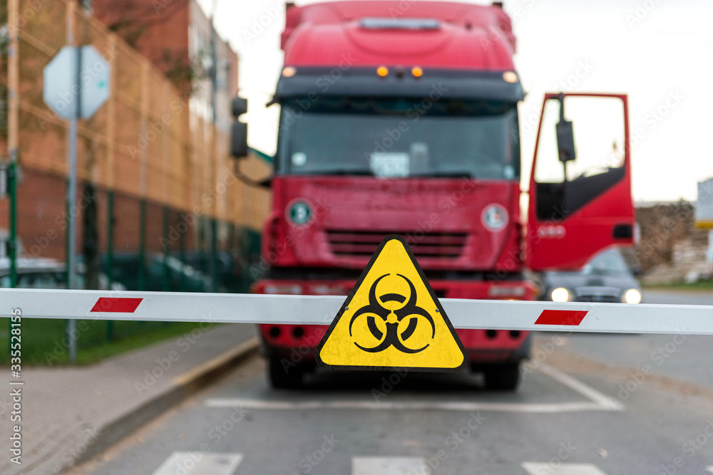 Truck standing at the barrier with a virus warning sign, Coronavirus containment concept Truck standing at the barrier with a virus warning sign, Coronavirus containment concept