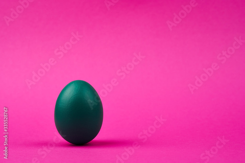 Colorful green easter egg on bright pink background