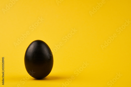 Colored black easter egg on bright yellow background