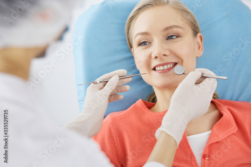 Smiling caucasian woman is being examined by dentist at dental clinic. Healthy teeth and medicine, stomatology concept