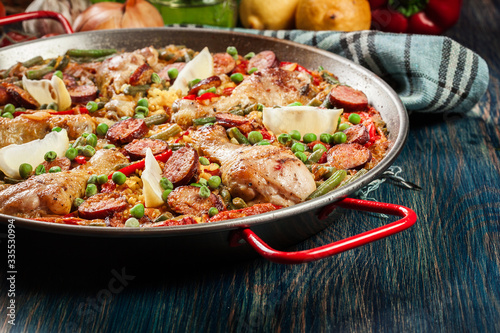 Traditional paella with chicken legs, sausage chorizo and vegetables served in paellera
