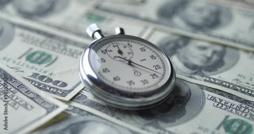 The stopwatch lies on the dollars. Time is money concept. The stopwatch lies on the dollars. Time is money concept.