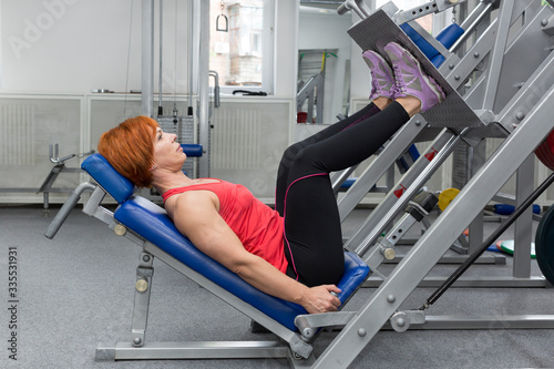 An elderly woman is engaged in power fitness in the gym. 