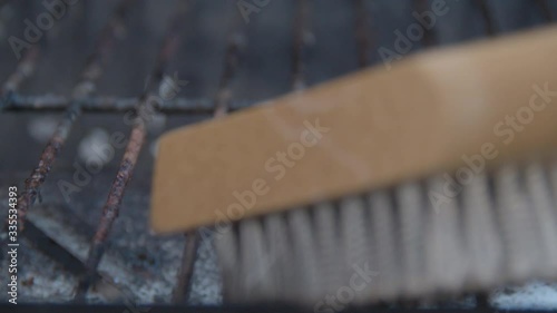 Scrubbing barbecue roster with a steel brush - extreme close photo