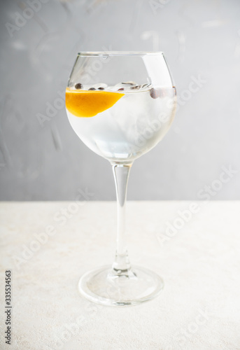 Gin based cocktail with lemon slice and juniper berries in wine glass. Selective focus. Shallow depth of field.