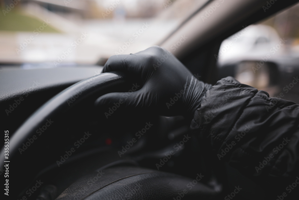 Φωτογραφία Details with the hand of a driver, in a latex glove, on a black steering wheel during the Covid-19 pandemic