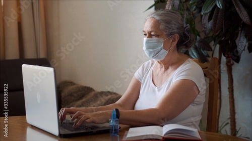 Coronavirus self isolation woman with medical mask spraying antibacterial gel 