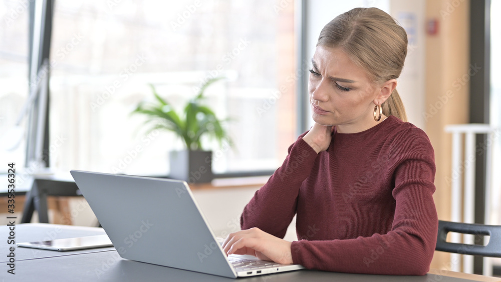 Young Woman with Neck Pain using Laptop in Office