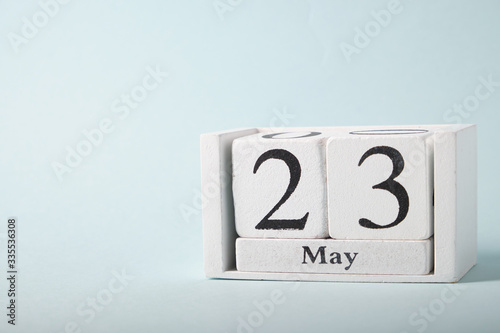 Wooden calendar on a blue background with the date of May 23