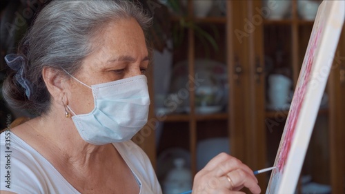 Coronavirus artist painting at home wearing hygienic mask to prevent infection