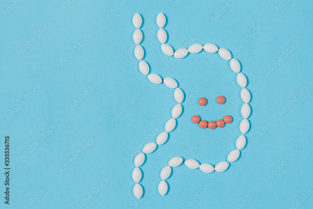 Different pills on a blue background. health and medicine. stomach with smile Different pills on a blue background. health and medicine. stomach with smile
