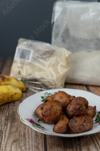 Popular Malaysian fritter snack deep fried banana balls or locally known as Cekodok Pisang in a plate over wooden background photo