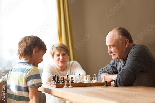 grand parent with grandson play chess together at home. quarantine. health concept. Corona Virus. Quality Time. Family having fun playing at home. stay home concept
