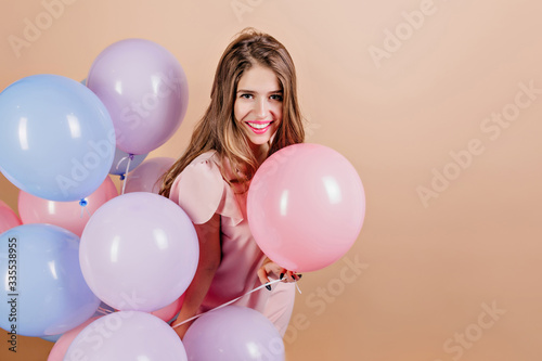 Winsome girl with bright makeup having fun at birthday party. Indoor photo of smiling gorgeous white woman with colorful balloons.