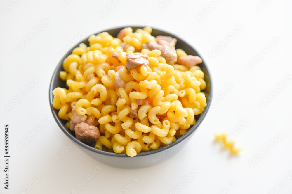 boiled macaroni with meat on a plate on a white background