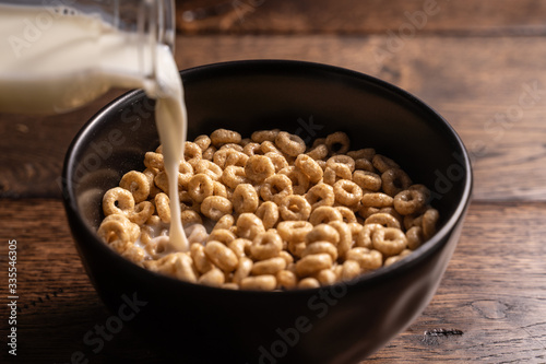 Zdjęcie płatków śniadaniowych z mlekiem w czarnej misce na drewnianym stole