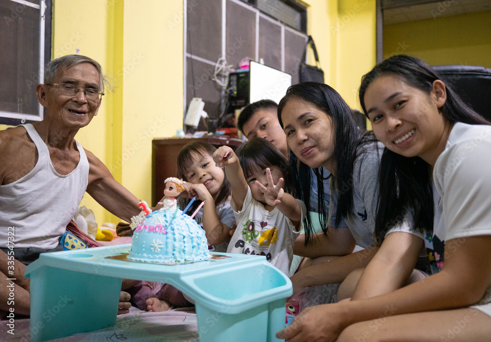 Fototapeta premium Happy family celebrating birthday to little daughter at home. Cute little girl blowing birthday cake. Concept of happy family and childhood.