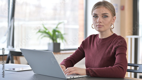 Young Woman with Laptop Looking at Camera in Office Free Download Young Woman with Laptop Looking at Camera in Office - GFXLoad