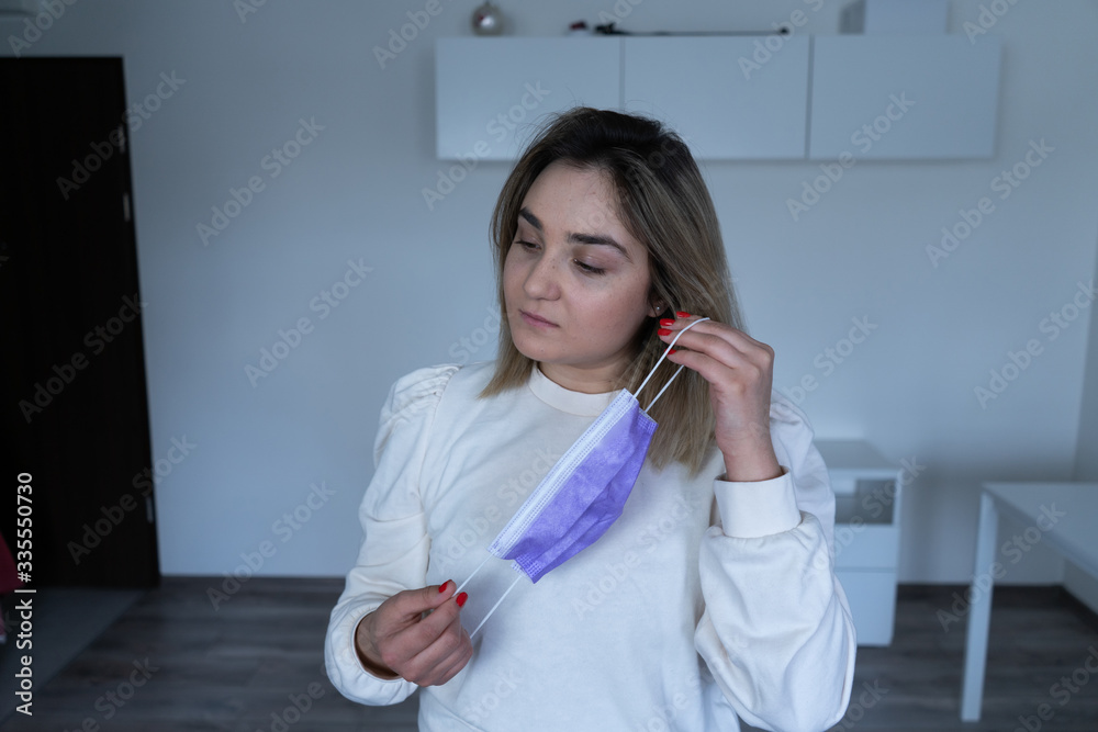 Woman puts on a protective medical mask. Beautiful girl with freckles puts on a protective mask Woman puts on a protective medical mask. Beautiful girl with freckles puts on a protective mask