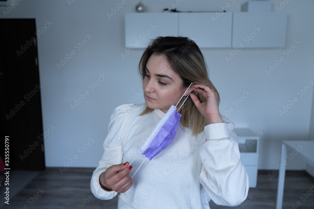 Woman puts on a protective medical mask. Beautiful girl with freckles puts on a protective mask Woman puts on a protective medical mask. Beautiful girl with freckles puts on a protective mask