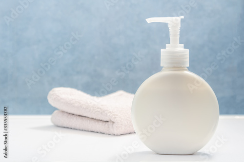 Personal hygiene products. Soap gel in a white plastic bottle and towel on the dressing table in the bathroom. There is a place for your text in the image.