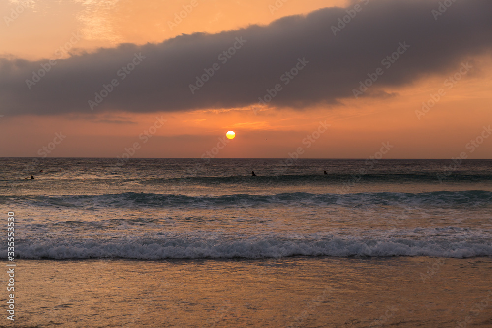 Obraz premium sunset on the beach, sky with orange colors and clouds, sea with small waves
