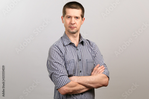 A worker in a cage shirt and tie crossed his hands on his chest. half-length portrait