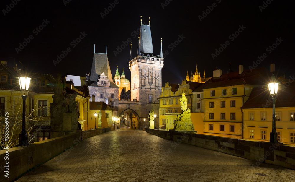 Obraz premium Night colorful Prague gothic Castle with St. Nicholas' Cathedral and Bridge Tower from Charles Bridge with its baroque Statues without People at the time of Coronavirus, Czech Republic