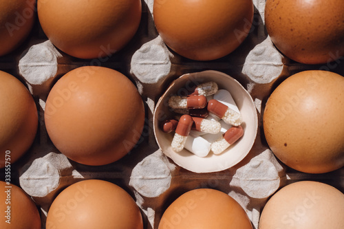 box with chicken eggs on a blue background. pills in
egg shell. concept idea health