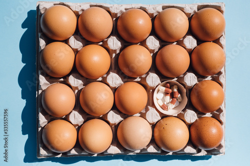 box with chicken eggs on a blue background. pills in
egg shell. concept idea health
