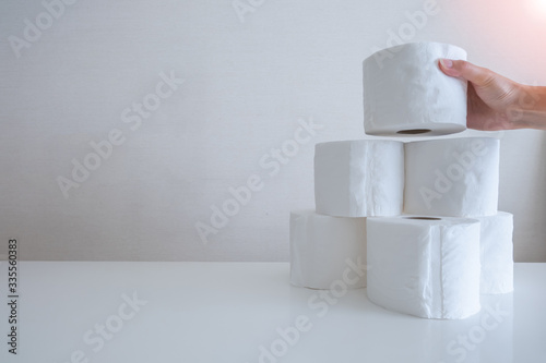 Photography A female hand grabbing one roll from a pile of toilet tissue paper rolls with during Coronavirus or Covid-19 outbreak with copy space