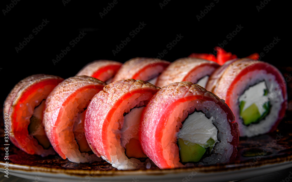 sushi roll with tuna, avocado, cream cheese, cucumber, rice in plate on black wooden table background sushi roll with tuna, avocado, cream cheese, cucumber, rice in plate on black wooden table background