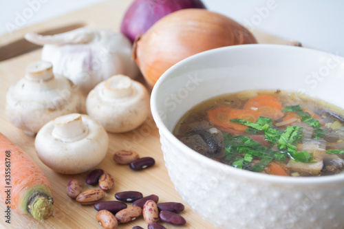 Healthy vegetable and bean soup with its ingredients: carrots, mushrooms, onions, garlic, herbs and kidney beans