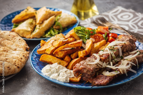 Souvlaki served with fried potatoes, tzatziki dip and pita bread, greek cuisine.