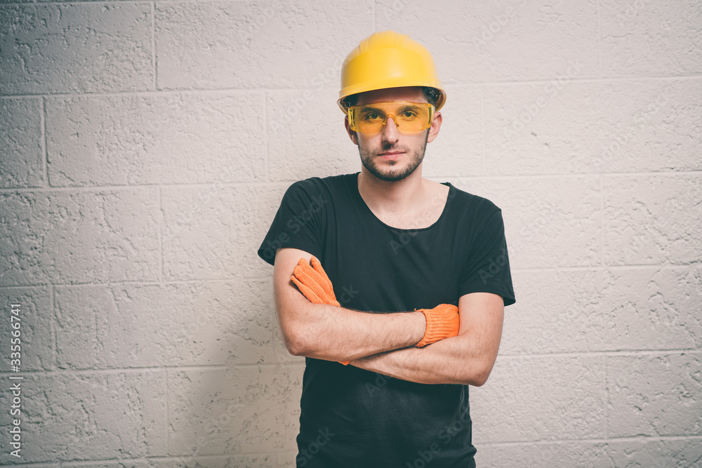 Handsome young man with protective helmet on his head and arms crossed Handsome young man with protective helmet on his head and arms crossed