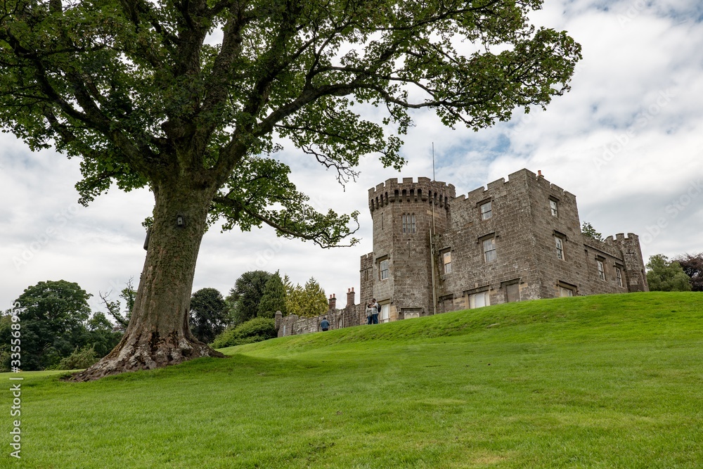 The wide-angle landscape shot of ancient Balloch Castle and a tree in Scotland, UK which was built on a hill in an early 19th century