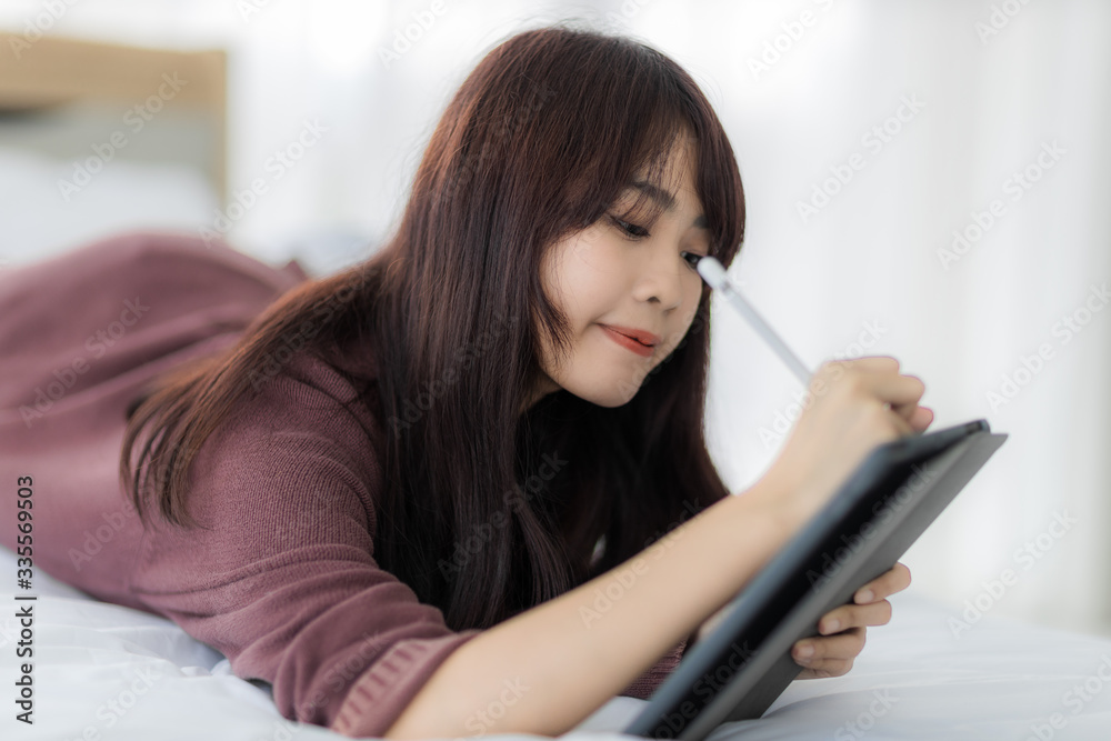 Asian woman using tablet for working, educational, e-commerce, social media in her bed. corovavirus covid-19, stay at home, work form home concept. Asian woman using tablet for working, educational, e-commerce, social media in her bed. corovavirus covid-19, stay at home, work form home concept.